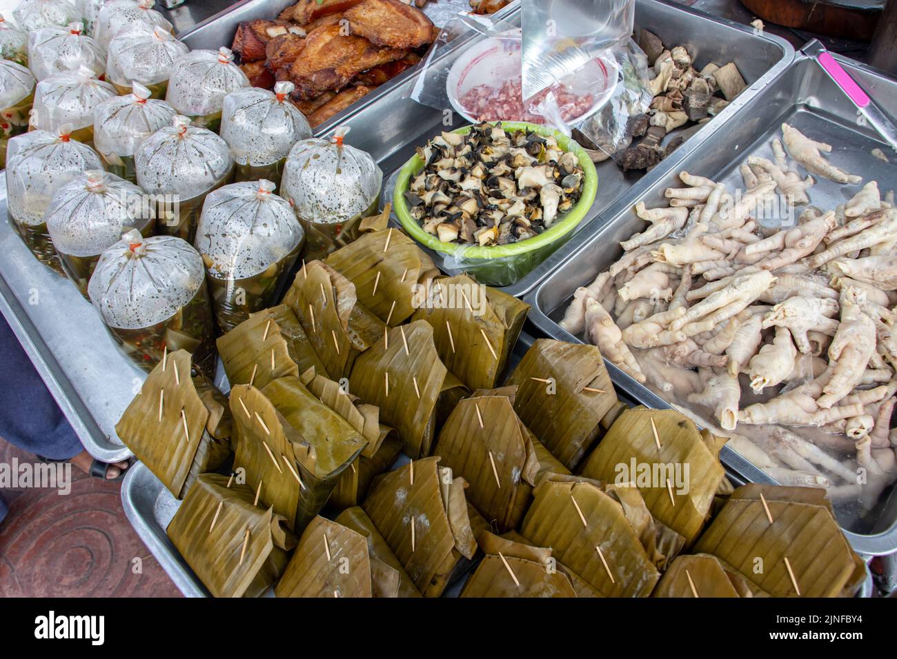L'offerta del mercato thailandese, zuppa di funghi in stile Isan in sacchetti di plastica, pesce al vapore in mousse di curry rosso avvolto in foglia e altro. Foto Stock