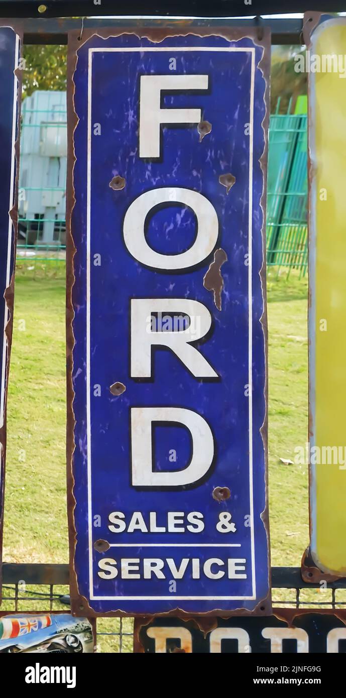 Vecchio arrugginito Ford vendite e servizio di pubblicità segno. Costruttore americano di automobili. Logo e marchio bianchi su sfondo blu. Foto Stock