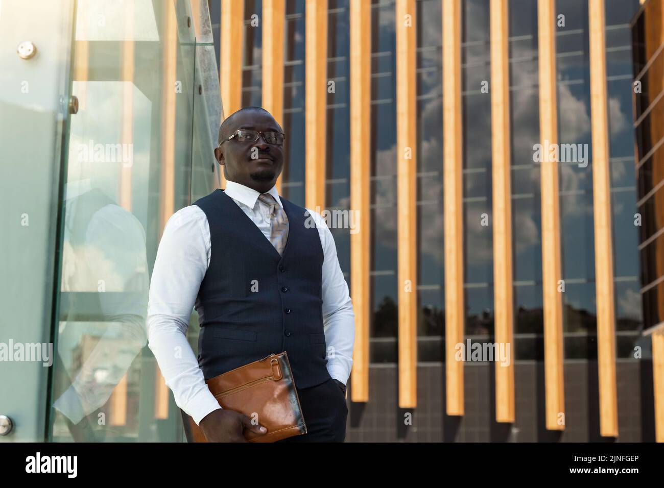 Ritratto di un uomo d'affari afro americano in tuta sullo sfondo di un edificio moderno esterno Foto Stock