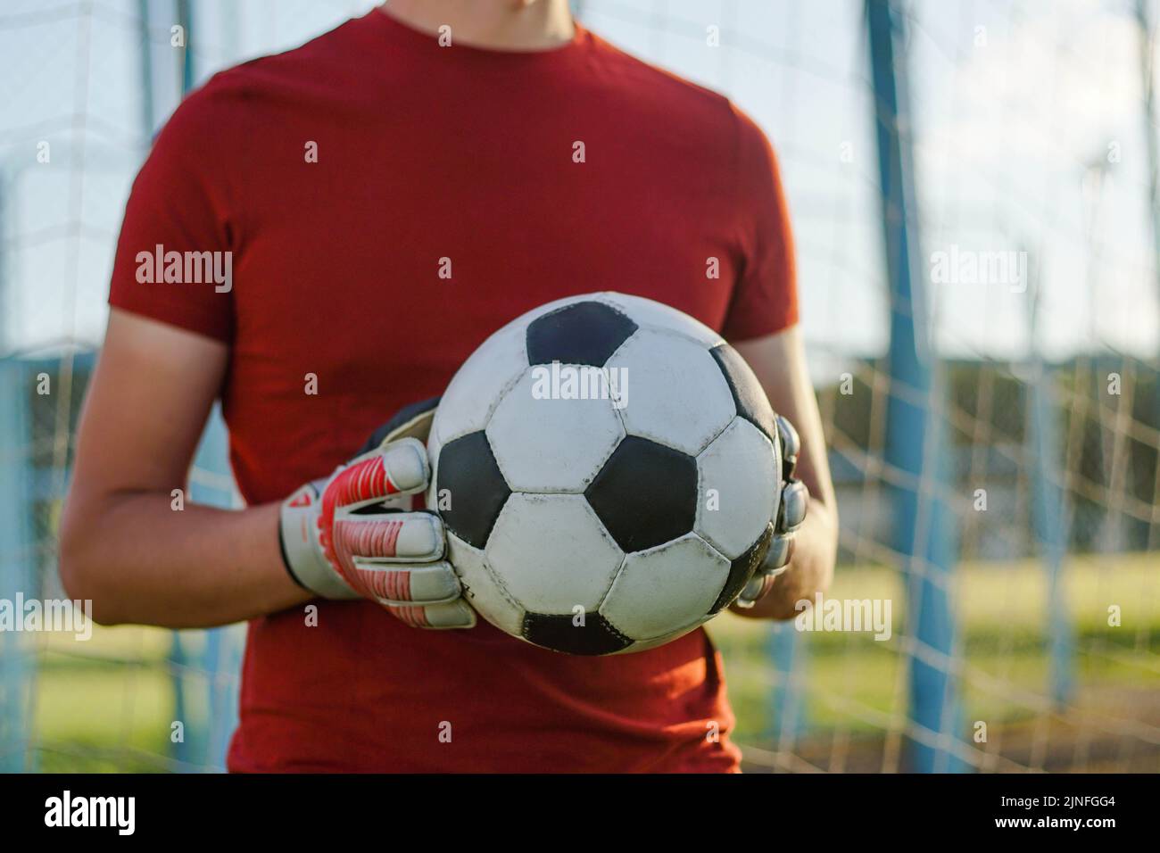 Ritratto di giovane calciatore portiere indossando guanti che tengono la palla da calcio. Foto Stock