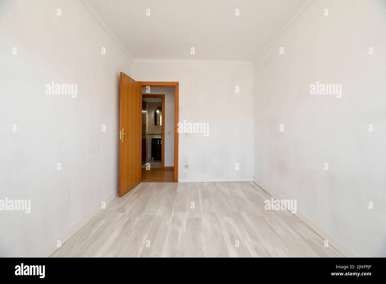 Camera vuota con pareti bianche, pavimenti in legno chiaro e lavori in legno sulle porte Foto Stock