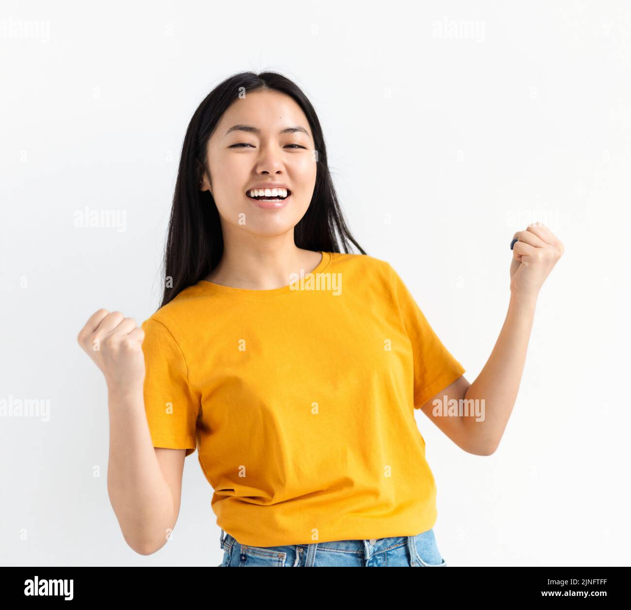 Ritratto di gioiosa donna asiatica gioire dire sì guardando felice e celebrando la vittoria in piedi su sfondo bianco Foto Stock