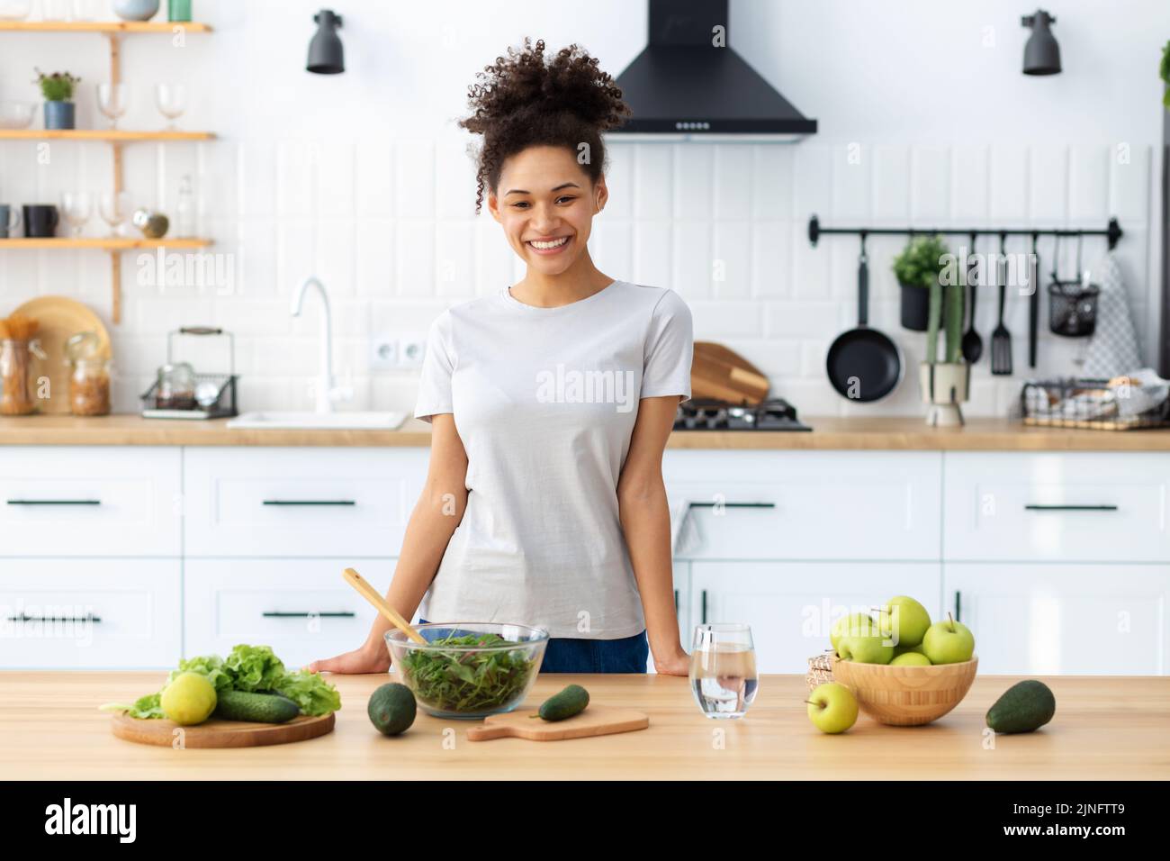 Dieta sana mangiare giovane ragazza afroamericana preparare insalata in casa cucina donna cucinare cibo sano Foto Stock