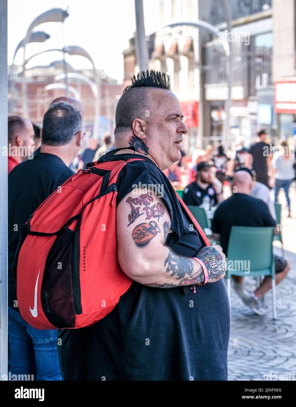 Blackpool, Lancashire, UK Agosto 6 2022 Un punk maschio con capelli neri spiky e che porta uno zaino rosso Foto Stock
