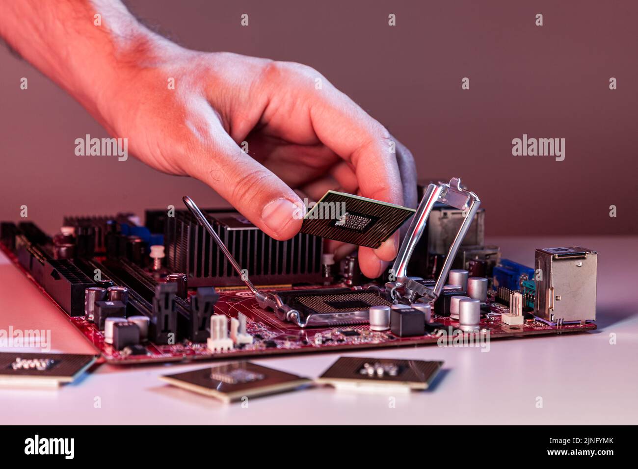 La mano di un uomo inserisce un processore nel chipset della scheda madre. Foto Stock