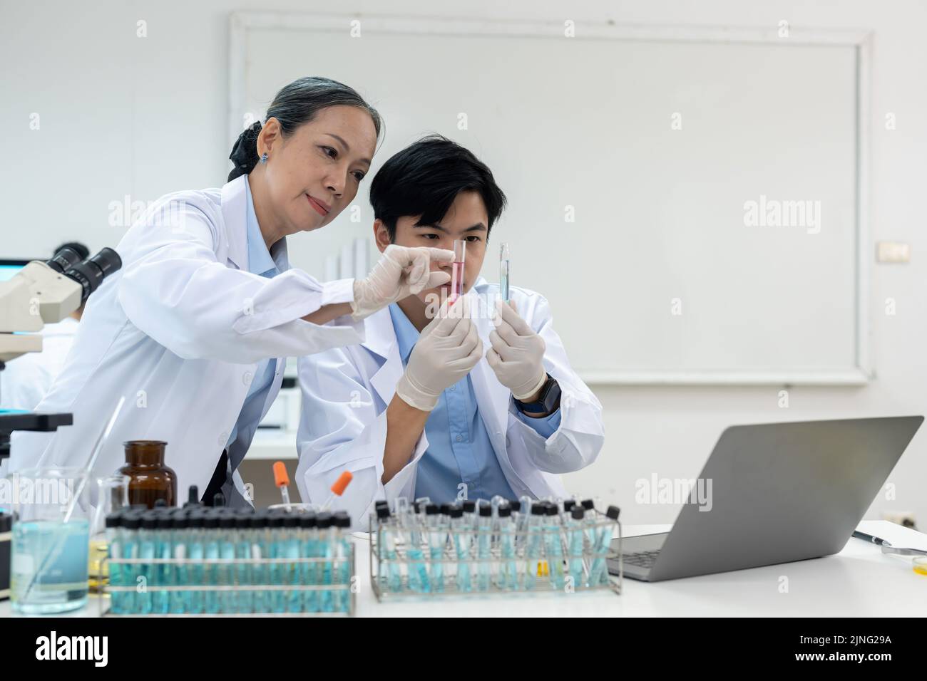 gruppo di scienziati della ricerca biochimica che lavora al microscopio per lo sviluppo di vaccini nella ricerca farmaceutica labolatoria. Foto Stock