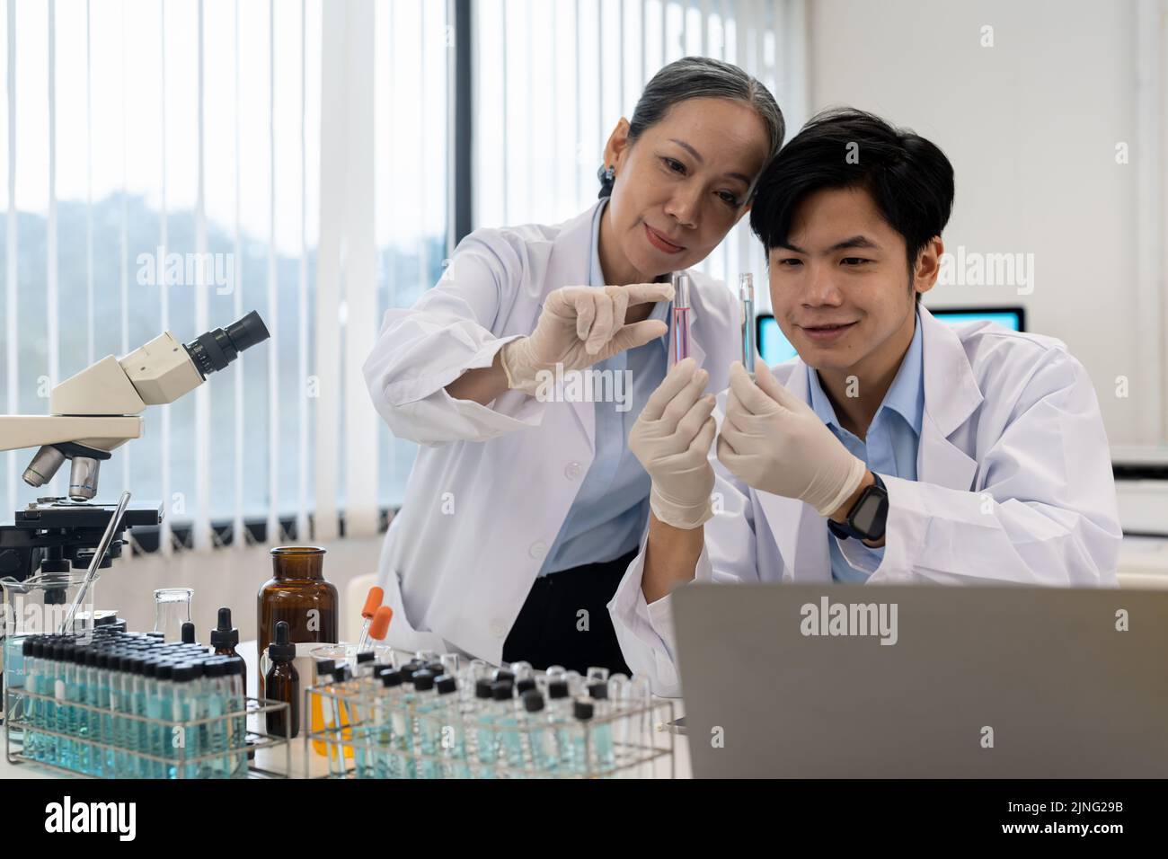 gruppo di scienziati della ricerca biochimica che lavora al microscopio per lo sviluppo di vaccini nella ricerca farmaceutica labolatoria. Foto Stock
