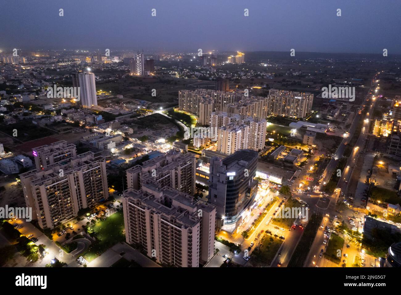 ripresa aerea del drone che mostra strade arancioni illuminate con grattacieli, torri che ospitano uffici di case e complessi commerciali tra la città Foto Stock