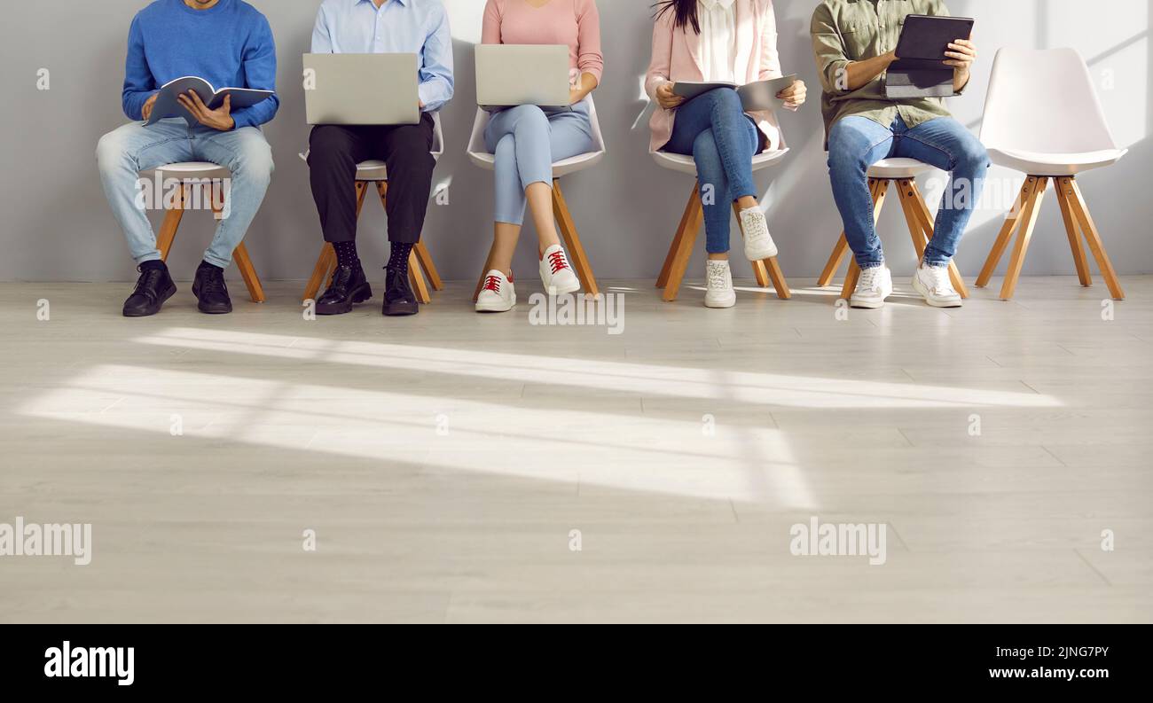 Foto ritagliata di persone aziendali che utilizzano notebook e tablet mentre aspettano in coda Foto Stock