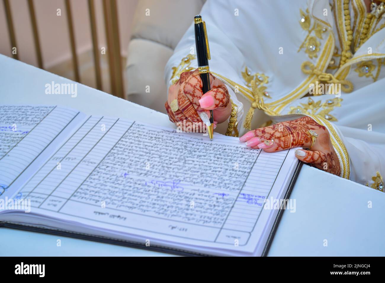 Una sposa araba firma il suo contratto di matrimonio con tatuaggi di henné sulle sue mani Foto Stock