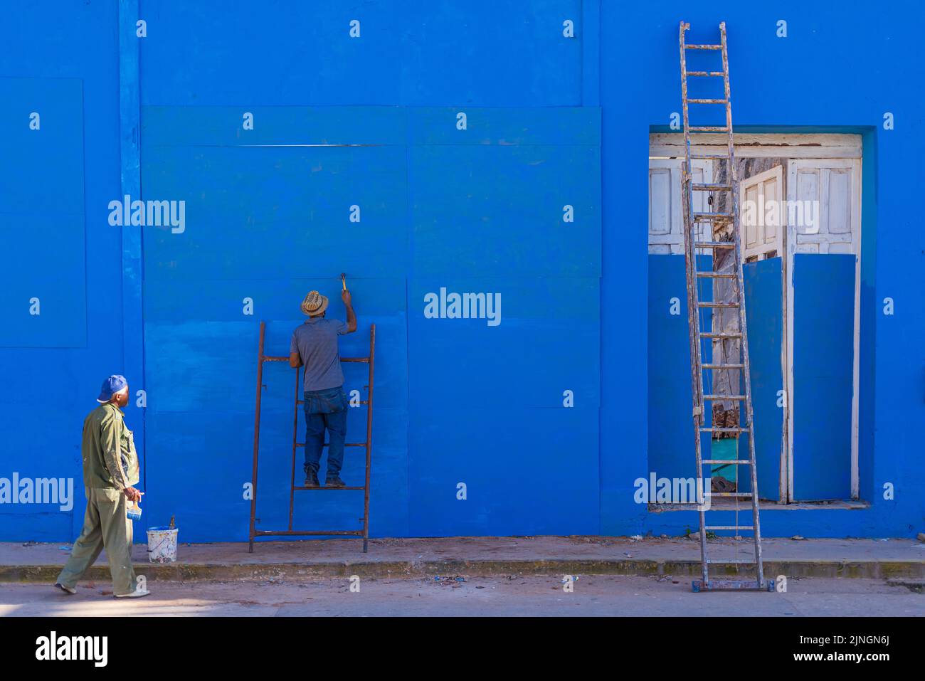 TRINIDAD, CUBA - 7 GENNAIO: Cubani dipingendo un muro blu a Trinidad il 7 gennaio 2021. Foto Stock