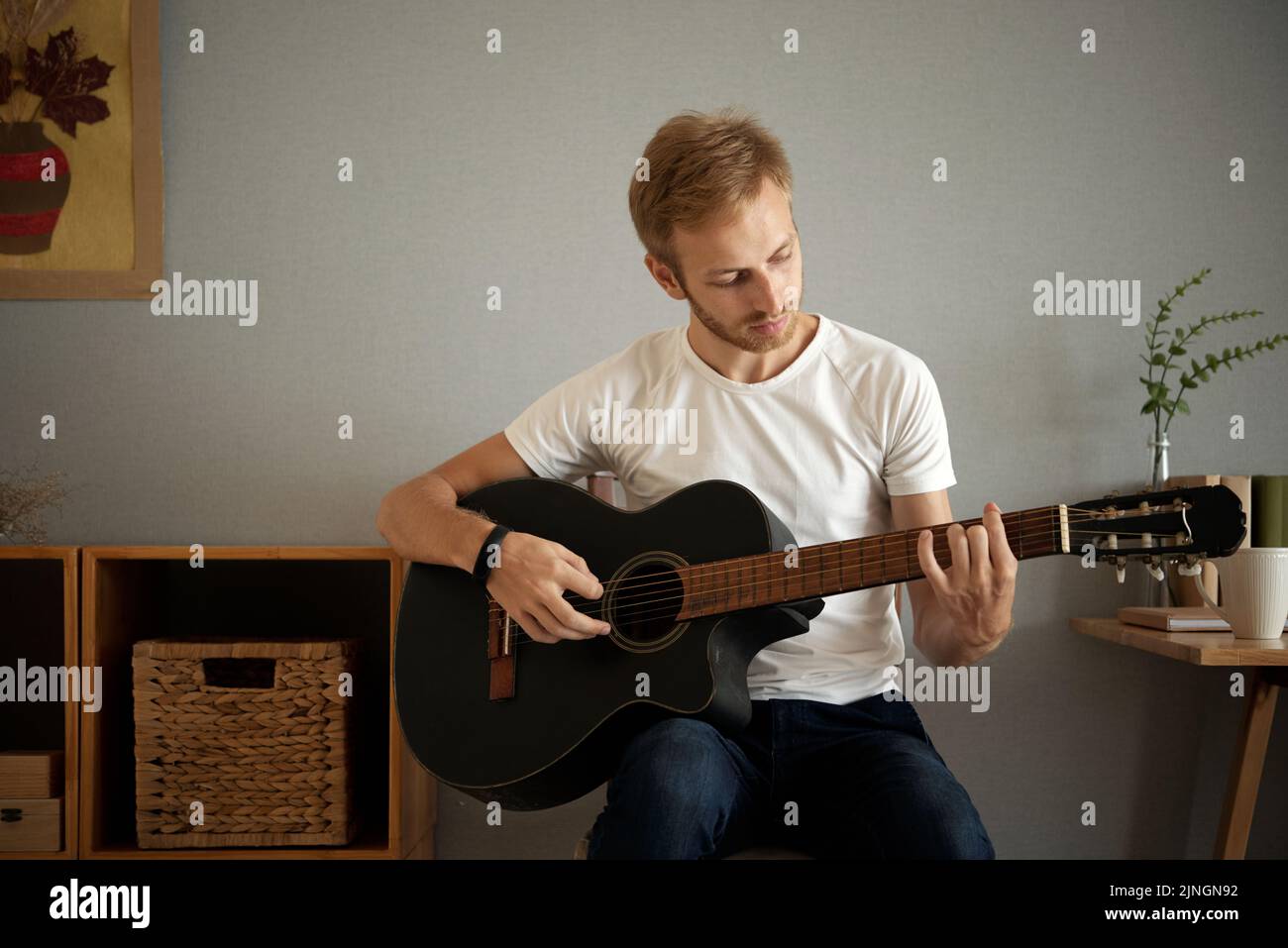 Bel giovane uomo che pratica la chitarra a casa Foto Stock