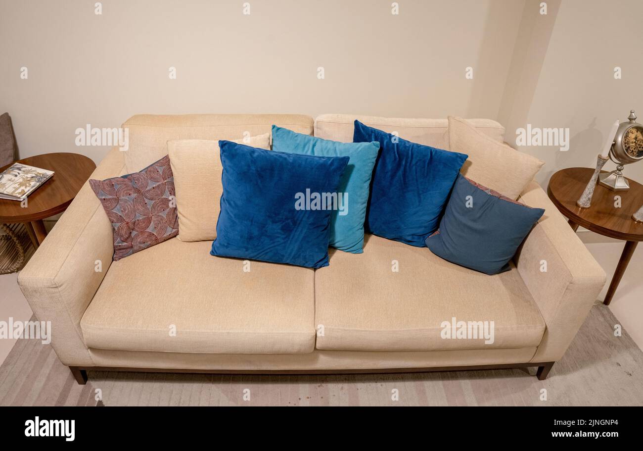 Un primo piano di un divano beige con splendidi cuscini in un soggiorno Foto Stock