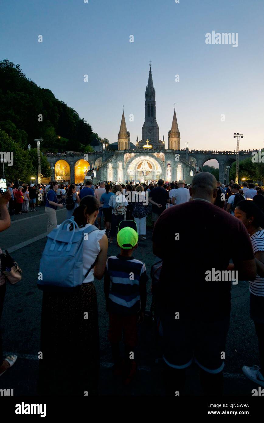 La gente si è radunata al Sanctuaires Notre-Dame de Lourdes Un pellegrinaggio cattolico. Notte Santuario di Santa Messa illuminato da candela di nostra Signora di Lourdes. Lourdes Processione. Foto Stock