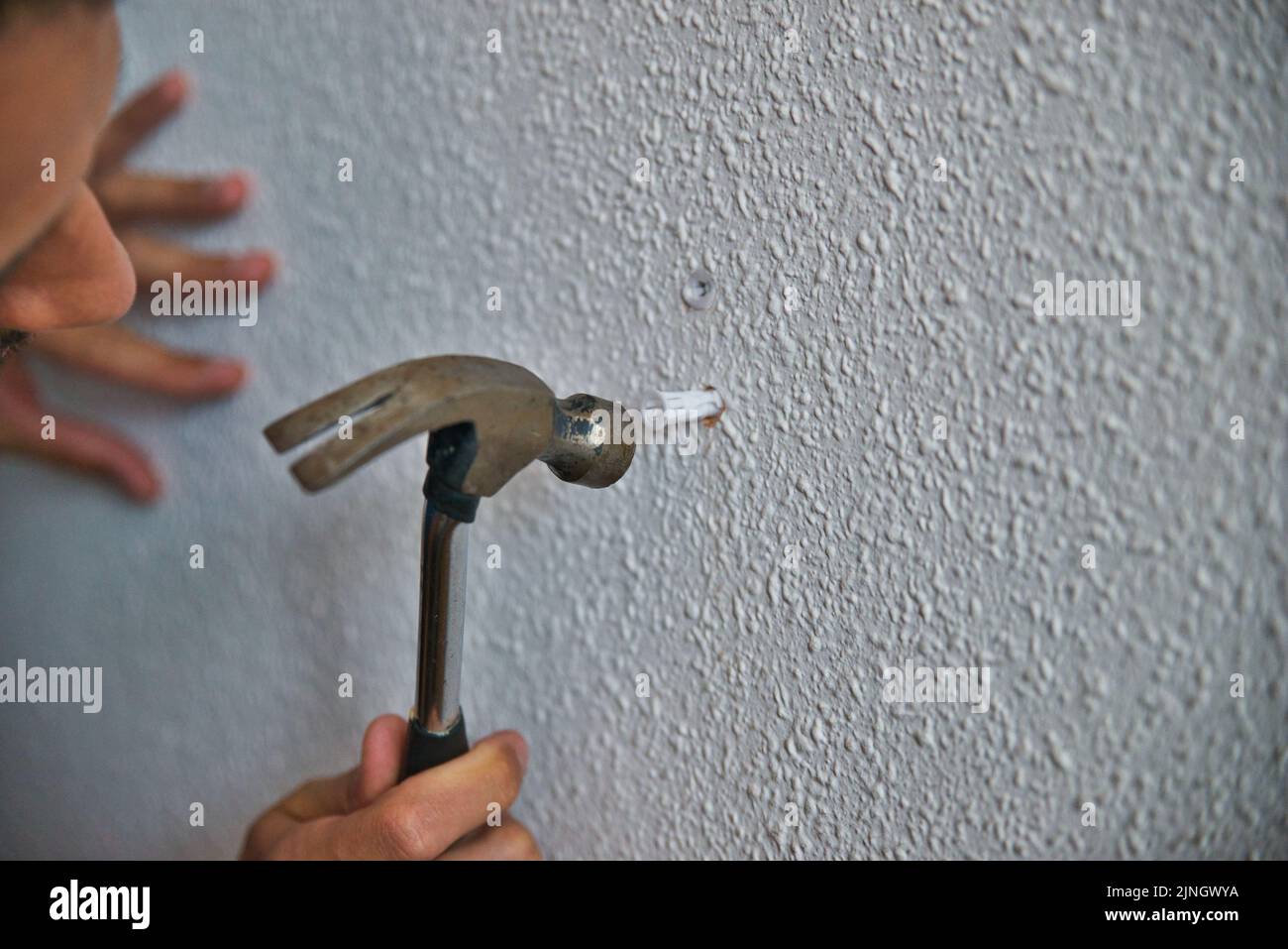 Falegname che lavora con attenzione, uomo martellando un muro. Lavorare a casa. Foto Stock