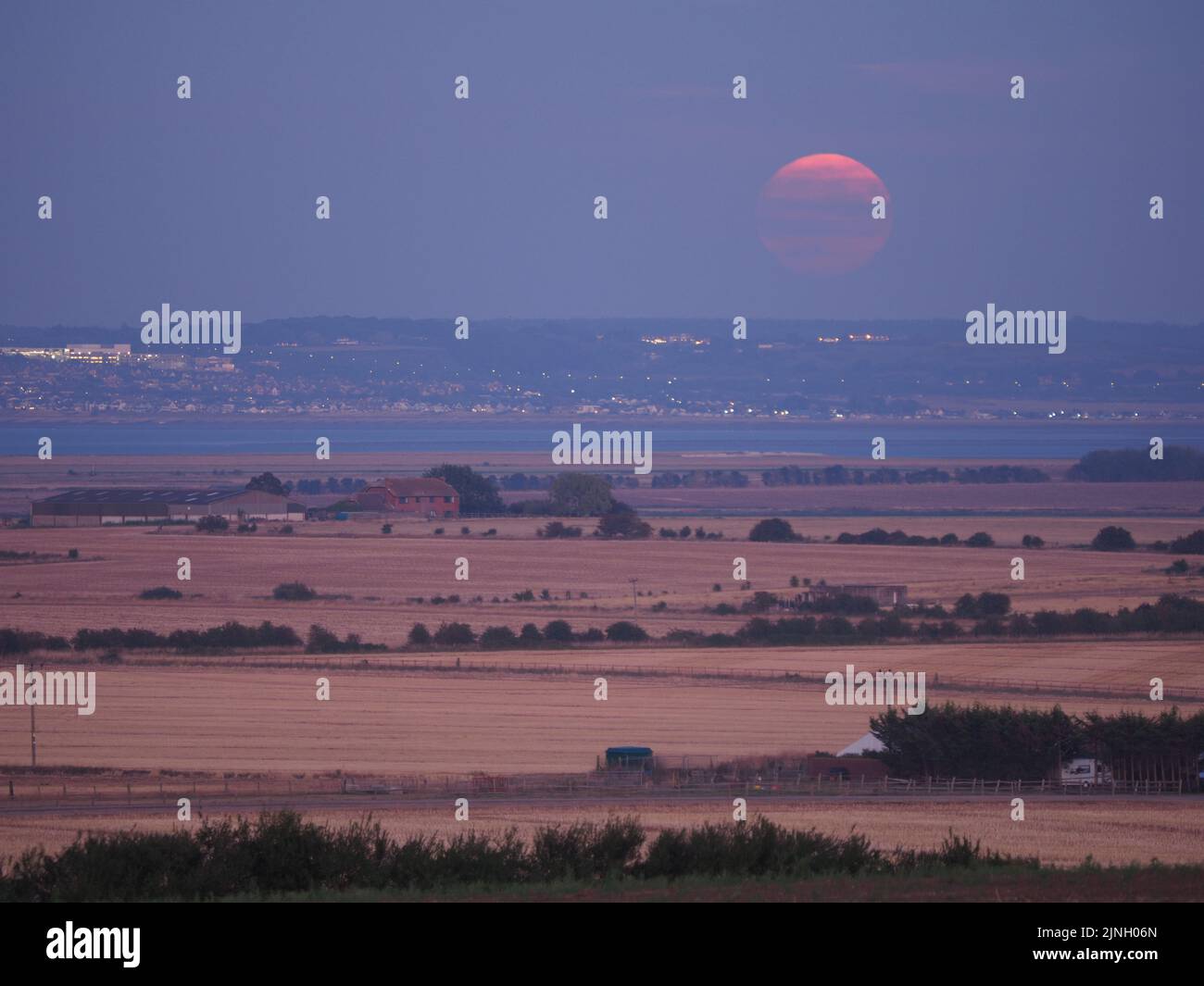 Eastchurch, Kent, Regno Unito. 11th ago, 2022. UK Weather: The full Sturgeon Moon - l'ultima superluna del 2022 - visto salire su campi arroccati in Eastchurch, Kent questa sera. Credit: James Bell/Alamy Live News Foto Stock