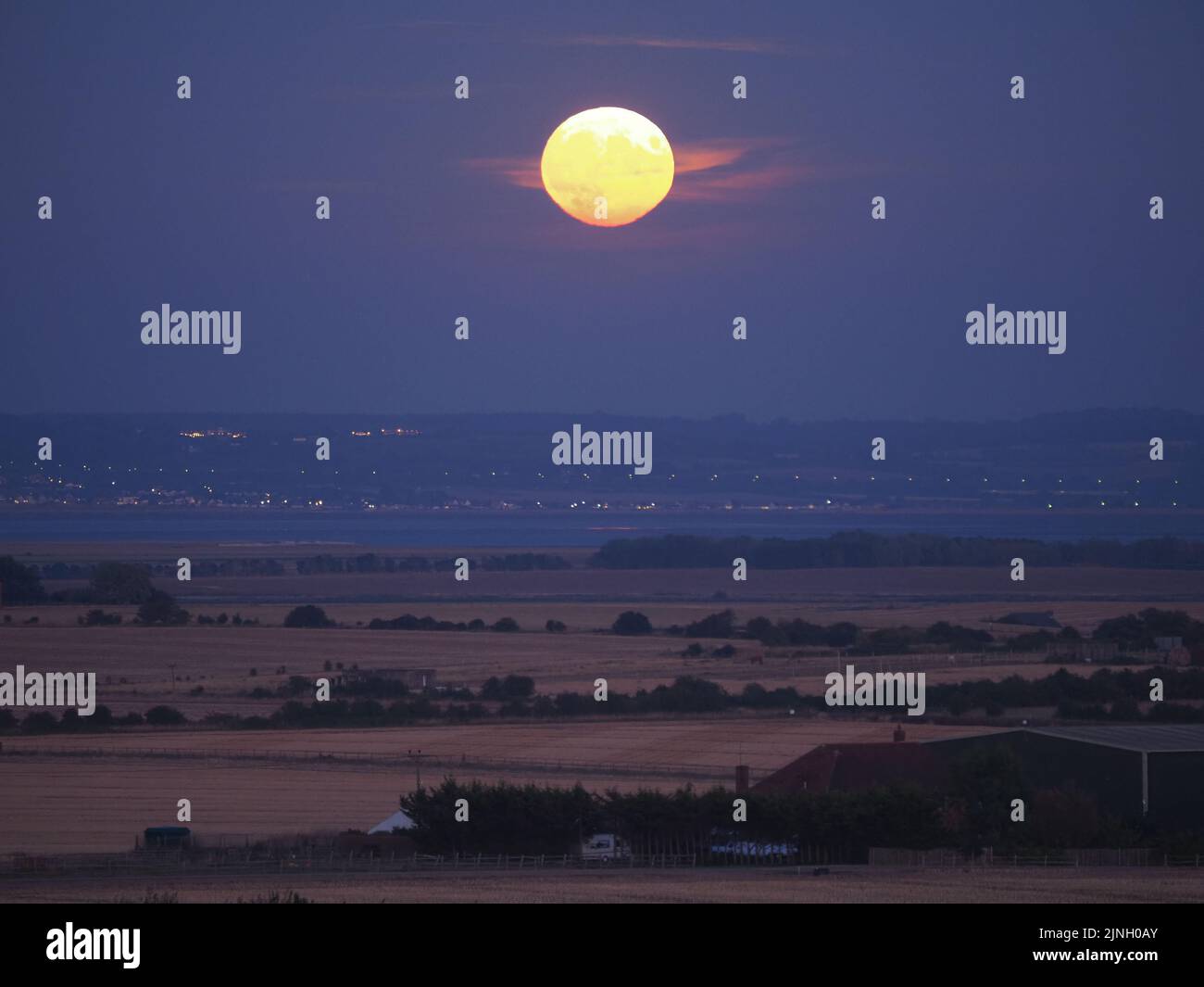 Eastchurch, Kent, Regno Unito. 11th ago, 2022. UK Weather: The full Sturgeon Moon - l'ultima superluna del 2022 - visto salire su campi arroccati in Eastchurch, Kent questa sera. Credit: James Bell/Alamy Live News Foto Stock
