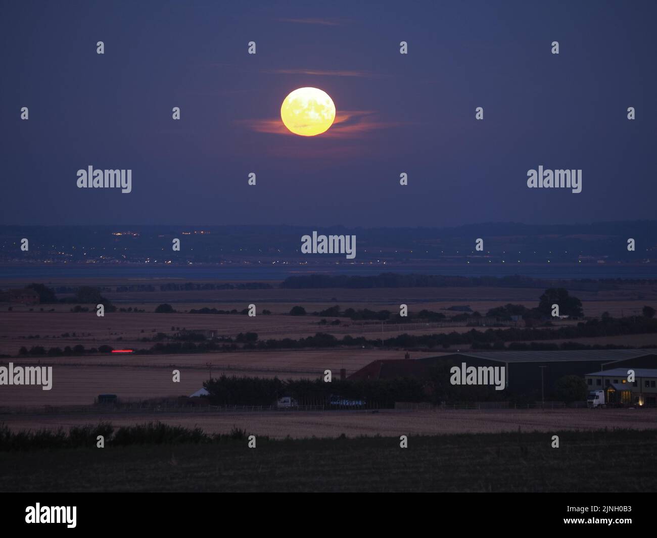 Eastchurch, Kent, Regno Unito. 11th ago, 2022. UK Weather: The full Sturgeon Moon - l'ultima superluna del 2022 - visto salire su campi arroccati in Eastchurch, Kent questa sera. Credit: James Bell/Alamy Live News Foto Stock