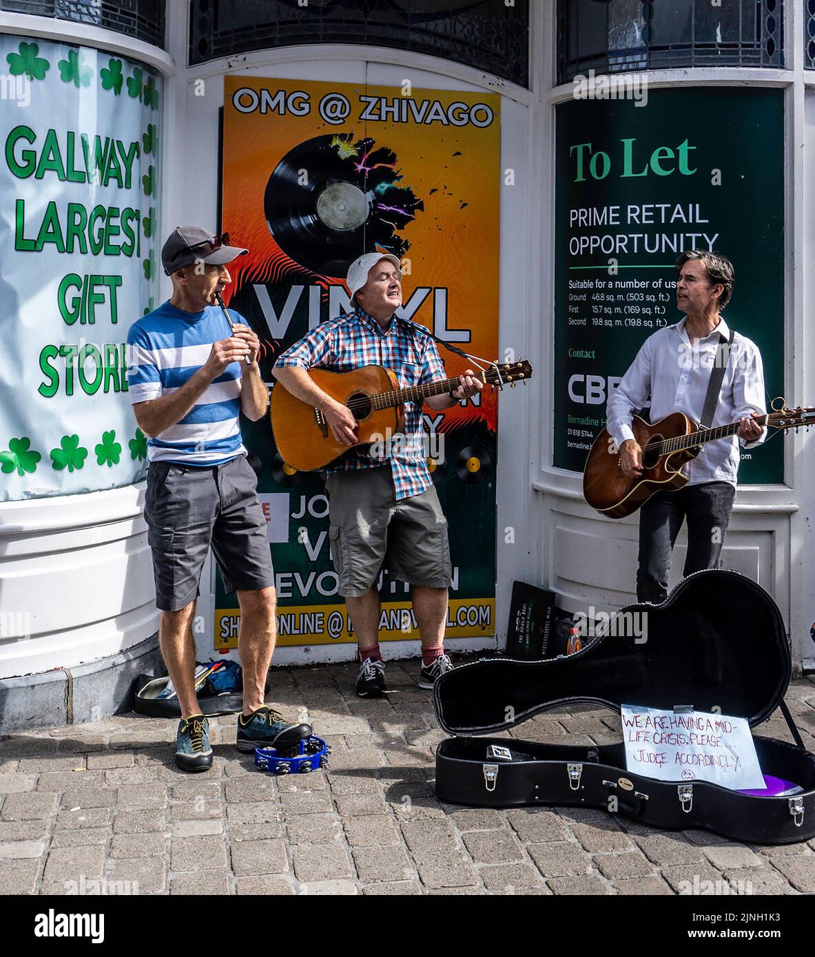 Un gruppo di uomini che bussano su Shop Street, Galway, Irlanda, il loro segno dice che stanno avendo una crisi di metà vita! Foto Stock
