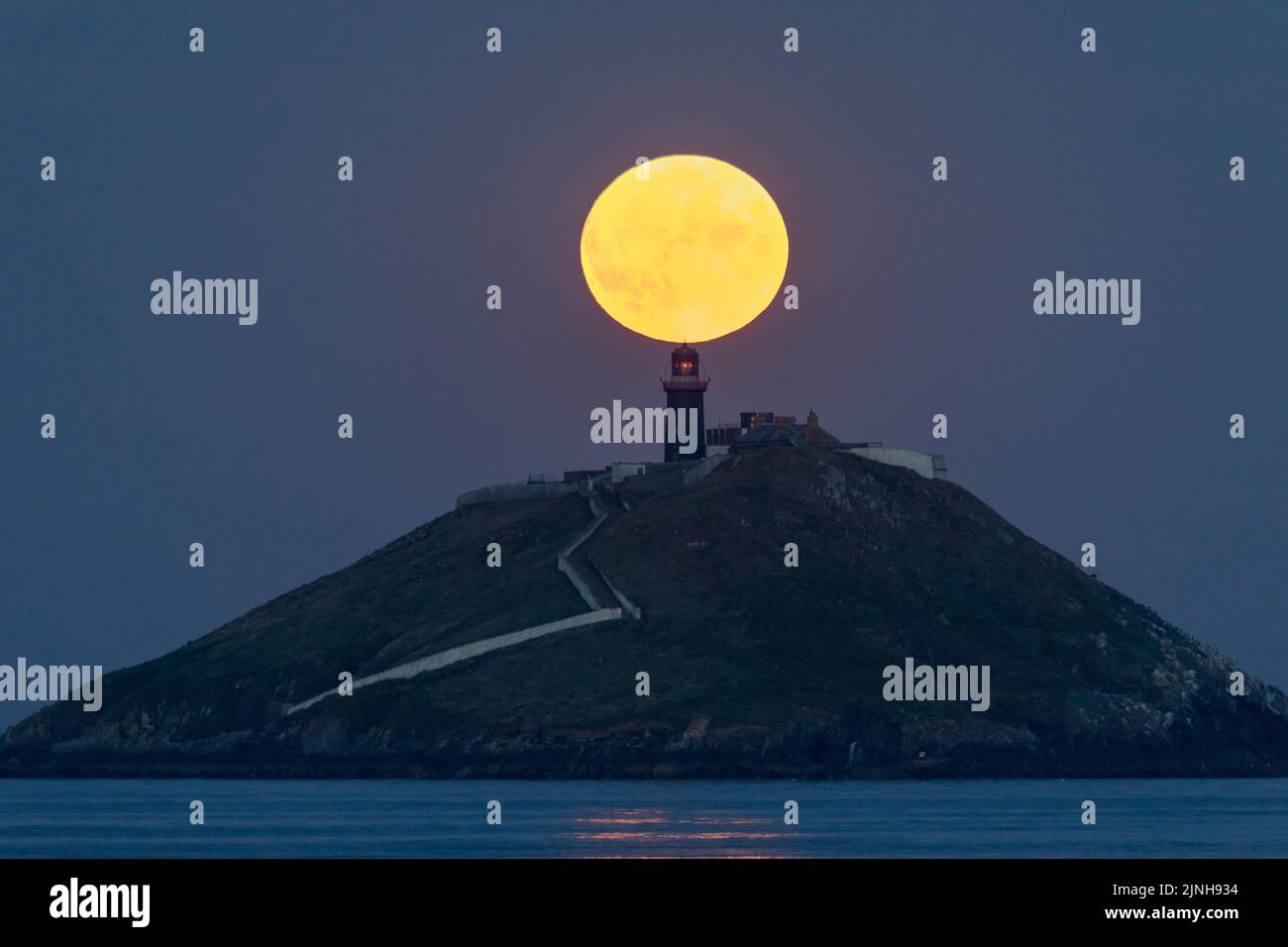 Ballycotton, Cork, Irlanda. 11th agosto, 2022. Una Sturgeon Moon sorge dietro il faro di Ballycotton Bay, Co. Cork, Irlanda. - Credit; David Creedon / Alamy Live News Foto Stock
