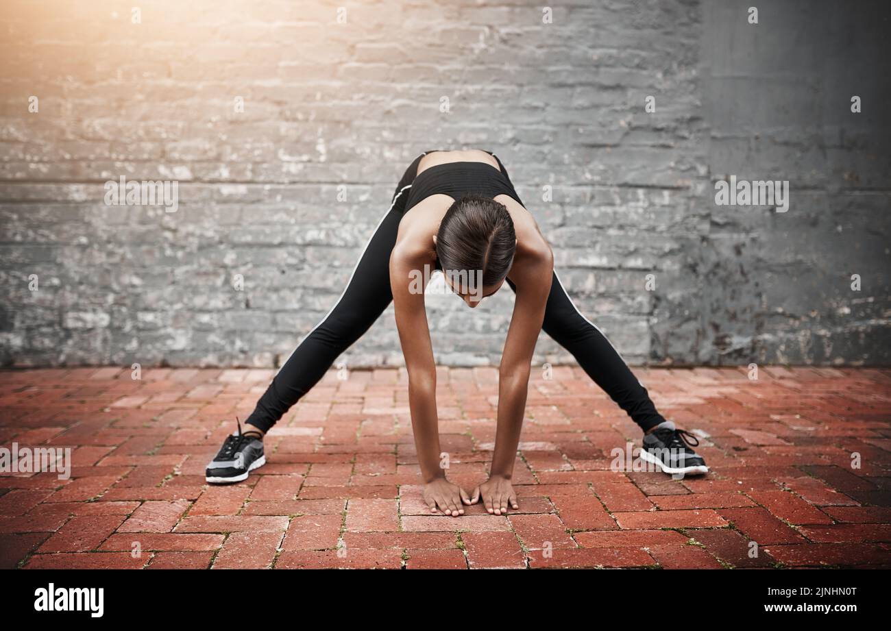 Sciogliendo e svegliando tutto il corpo, una giovane donna sportiva che si esercita all'aperto. Foto Stock
