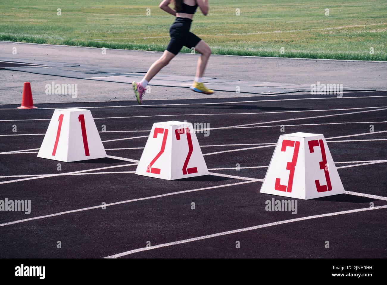piste da corsa allo stadio. la linea di partenza sulla pista sullo sfondo di una ragazza in corsa offuscata in movimento. stadio di atletica Foto Stock