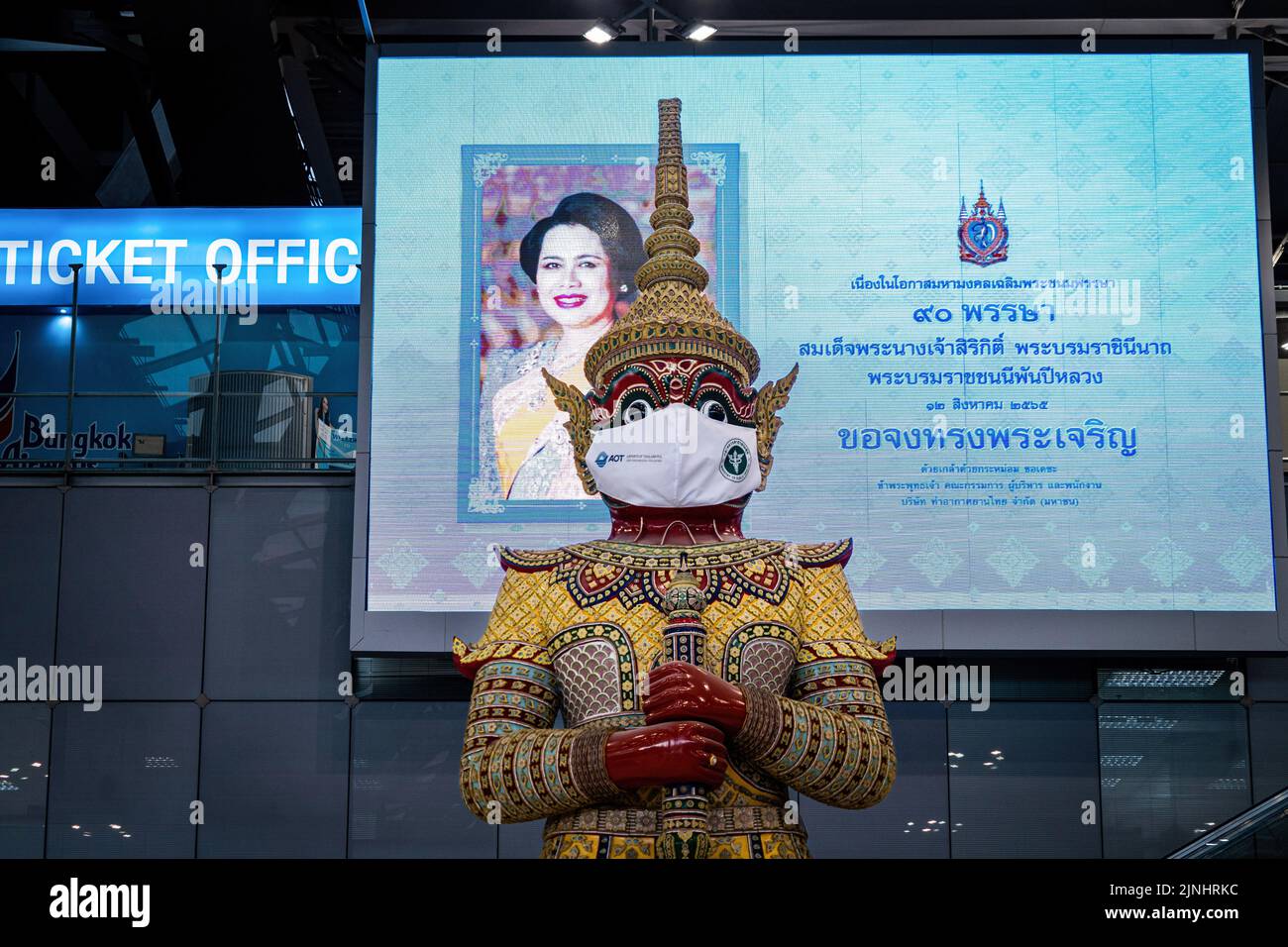 Bangkok, Thailandia. 12th ago, 2022. Una statua di Ramayana che indossa una maschera facciale è vista di fronte a un tabellone che rende omaggio alla Regina Madre, HM Regina Sirikit, il Motherís giorno all'Aeroporto Internazionale di Suvarnabhumi (BKK). Il turismo internazionale continua a rimbalzo in Thailandia, con 3 milioni di arrivi stranieri segnalati tra gennaio e luglio 2022. In un seminario del 10 agosto, il ministro delle Finanze della Thailandia, Arkhom Termpittayapaisith, ha dichiarato che gli arrivi internazionali dovrebbero raggiungere i 10 milioni di persone entro la fine del 2022. Credit: SOPA Images Limited/Alamy Live News Foto Stock