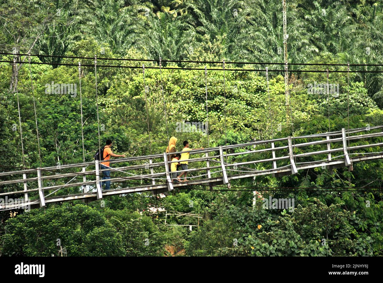 Persone che camminano su un ponte sospeso, attraversando il fiume Bahorok a Bukit Lawang, Bahorok, Langkat, Sumatra settentrionale, Indonesia. Foto Stock
