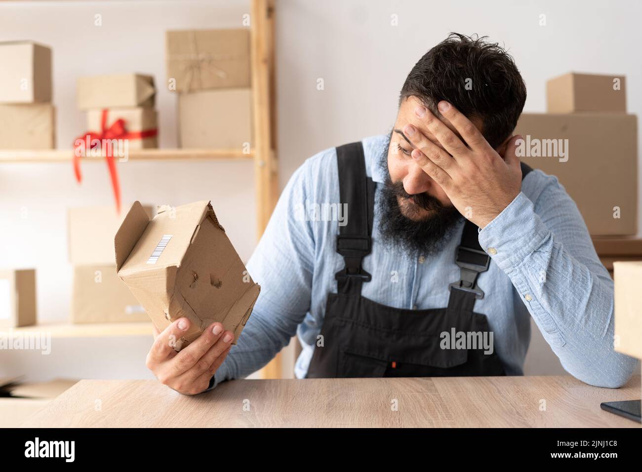 Imprenditore che tiene una scatola sbriciolata con le merci che lavorano nel servizio di consegna. Carico danneggiato al momento della consegna Foto Stock