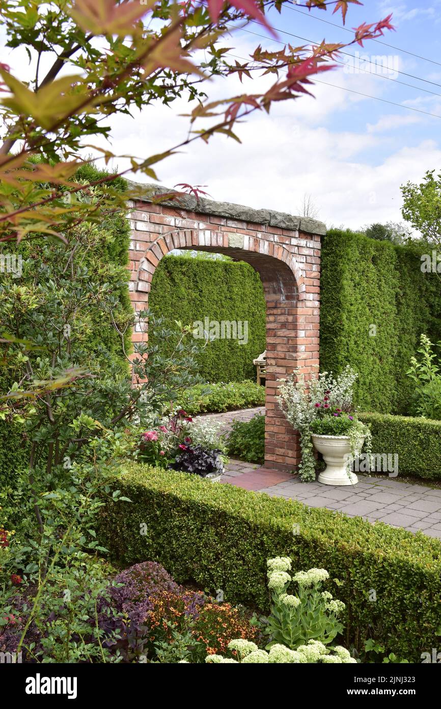 Mostra giardino, verde giardino interno circondato da una siepe thuja, vasi di fiori e bassi bordi tagliati. Foto Stock
