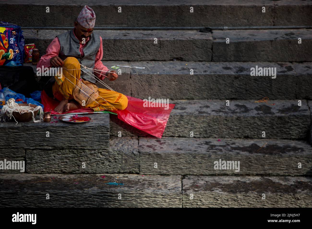 Kathmandu, Nepal. 12th ago, 2022. Un sacerdote organizza il Janai durante il festival di Janai Purnima nei locali del tempio di Pashupatinath a Kathmandu, Nepal, 12 agosto 2022. Durante questo festival, gli indù prendono il bagno santo ed effettuano il cambio annuale del Janai, una corda sacra di cotone indossata intorno al loro petto o legata sul polso, nella convinzione che proteggerà e purificherà loro. Credit: Sulav Shrestha/Xinhua/Alamy Live News Foto Stock