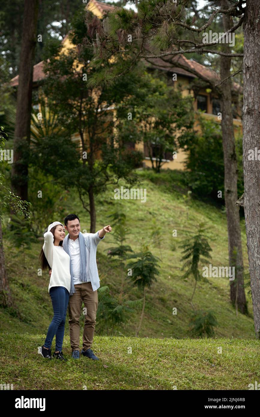 Felice giovane coppia asiatica che guarda in lontananza mentre cammina nel bosco Foto Stock