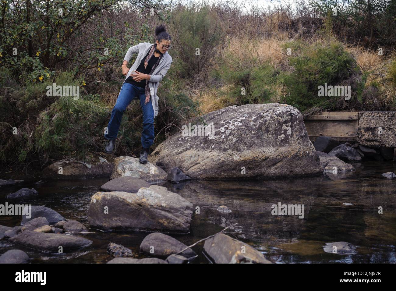 Equilibrio su pietre naturali passo attraverso un fiume nella valle di Kamberg in Sud Africa Drakensberg montagne Foto Stock