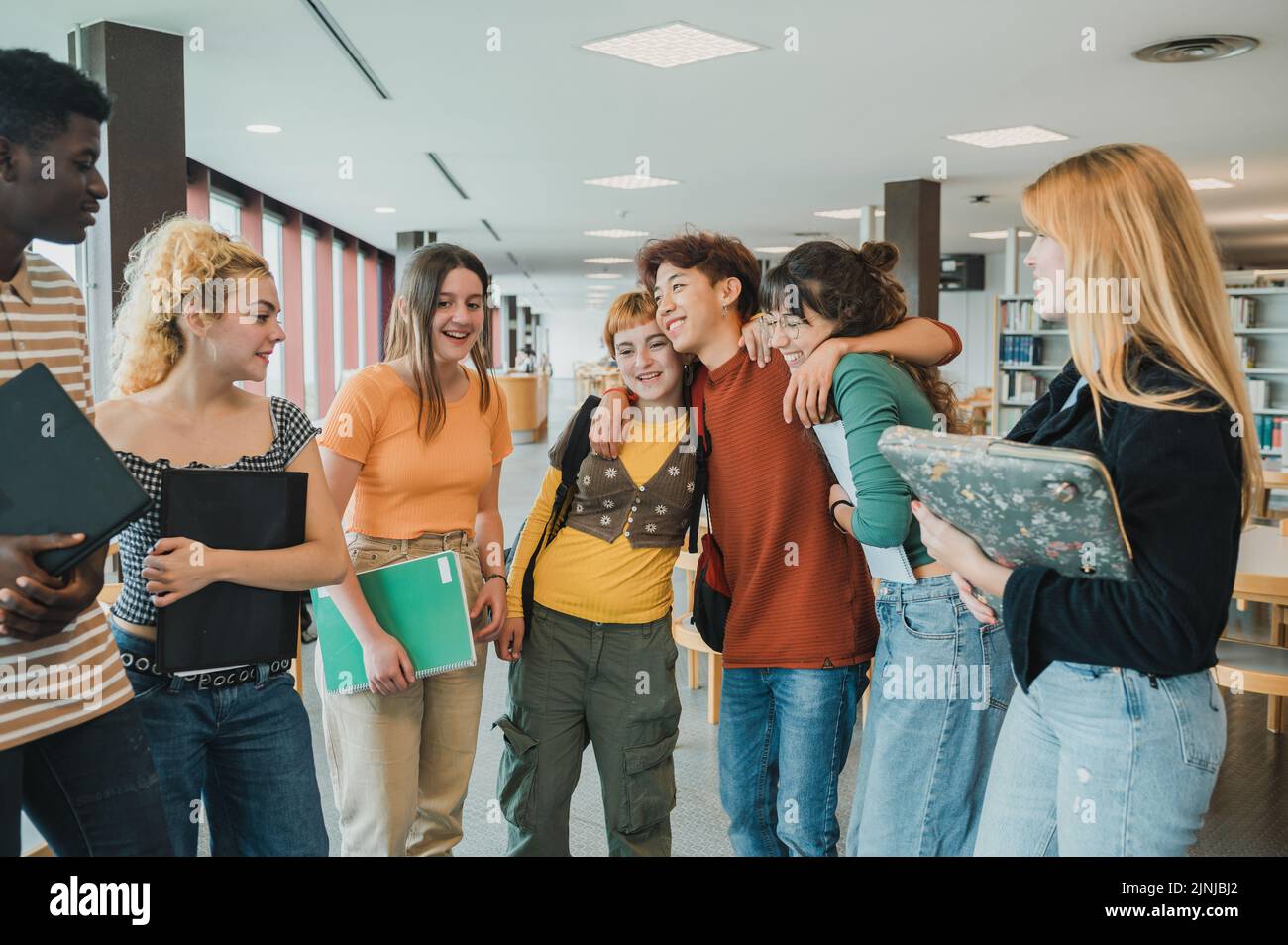 Studenti teenager multirazziali che abbraccia la biblioteca Foto Stock