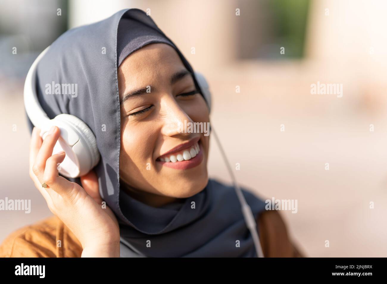 Donna musulmana godendosi mentre ascolta la musica all'aperto Foto Stock