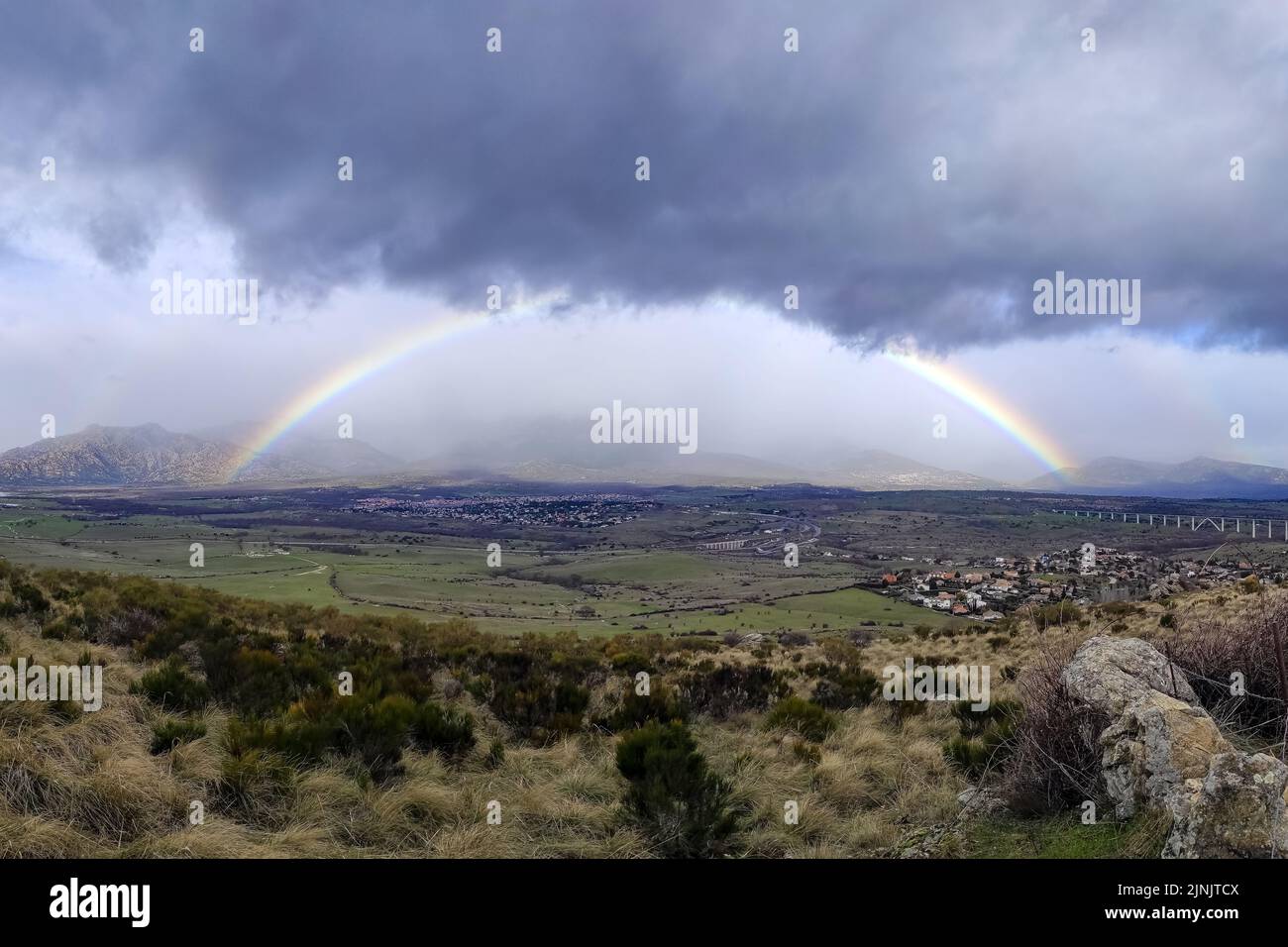 Spettacolare arcobaleno sulle montagne di Madrid, cielo con nuvole di pioggia scure. Spagna. Foto Stock