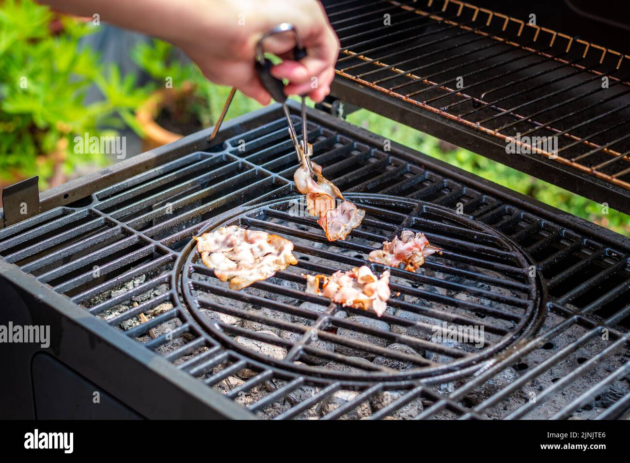 Cottura con pancetta sulla griglia calda, preparazione di cibi malsani. Foto Stock