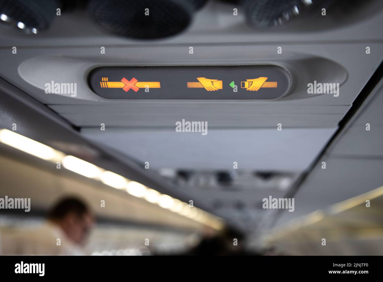 I segnali di divieto in aereo mostrano sigaretta attraversata e la raccomandazione di allacciare in su Foto Stock