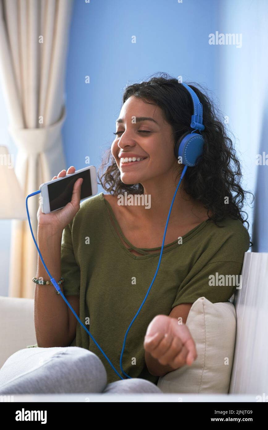 Felice bella giovane donna che ascolta la musica sul suo smartphone Foto Stock