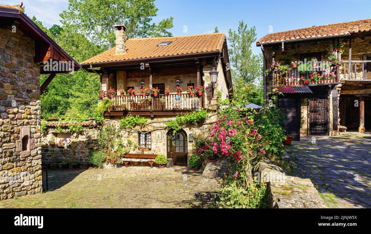 Pittoresche case in pietra in villaggio di montagna con piante e fiori. Barcena sindaco. Foto Stock