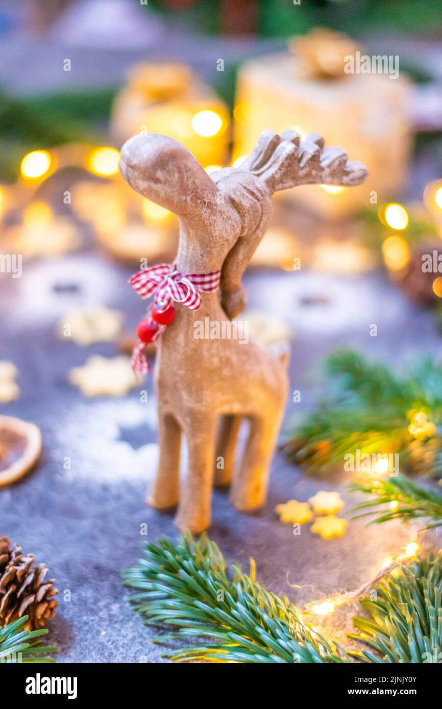 Statua del giocattolo in legno di renna di Natale con pino, cono e luce invernale sullo sfondo. Foto Stock