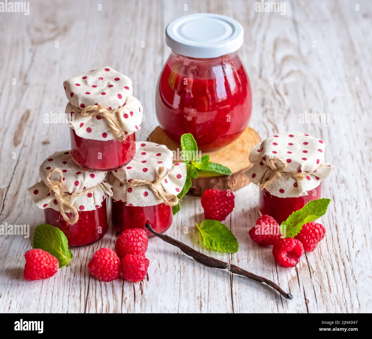 La marmellata di lamponi in piccoli bicchieri è posta su una scrivania di legno. Marmellata fatta in casa di lamponi freschi. Cucina fresca e sana. Foto Stock