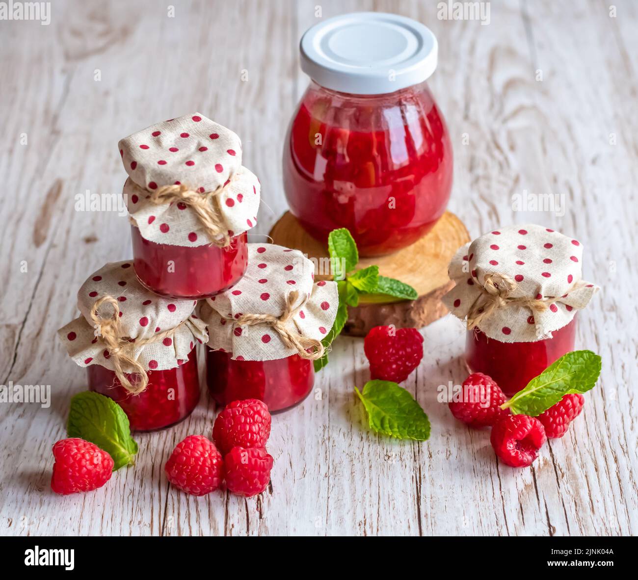 La marmellata di lamponi in piccoli bicchieri è posta su una scrivania di legno. Marmellata fatta in casa di lamponi freschi. Cucina fresca e sana. Foto Stock
