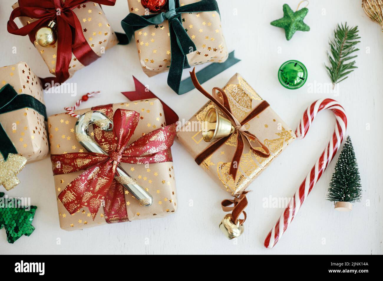 Buon Natale e buone feste! Elegante regalo di natale piatto lay. Scatole regalo di natale confezionate in stile moderno, carta dorata, nastri rossi e verdi, orname Foto Stock