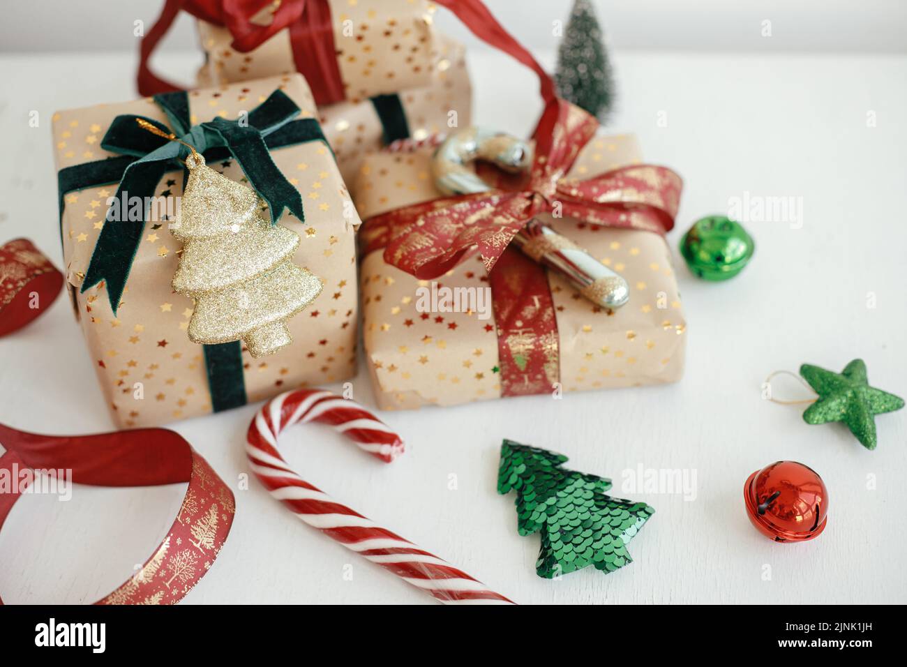 Buon Natale e buone feste! Eleganti regali di natale. Scatole regalo di natale confezionate in stile moderno, carta dorata, nastri rossi e verdi, compo ornamentali Foto Stock