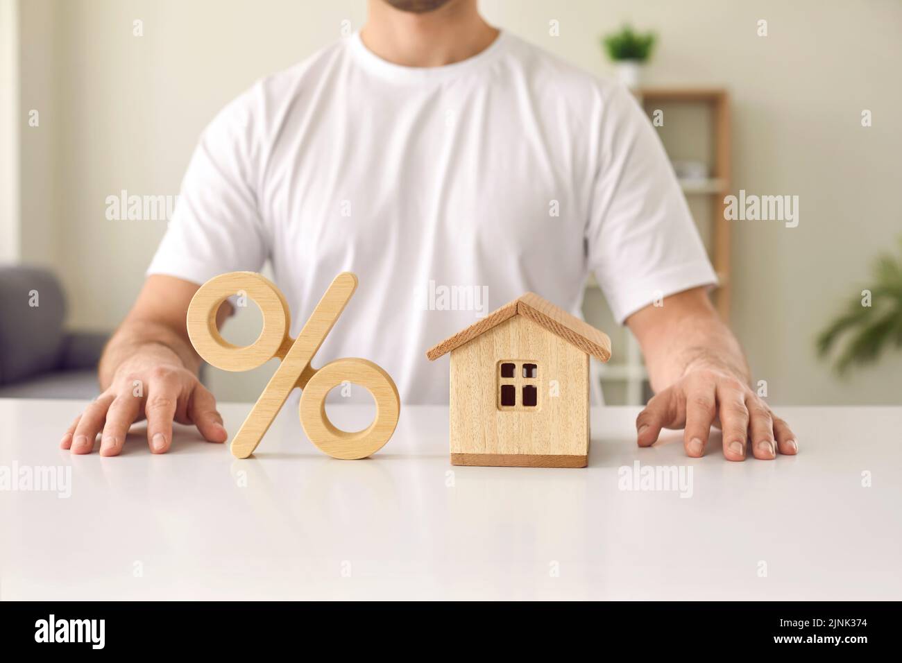 Uomo a tavola con la casa e simbolo di percentuale che illustra il concetto di tassi di interesse ipotecari Foto Stock