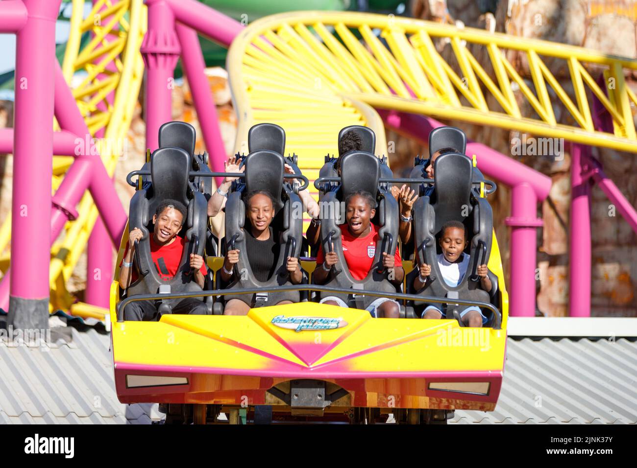 Roller coaster car con felici bambini eccitati volti sorridenti e godersi una giornata di estate brillante. Primo piano Foto Stock