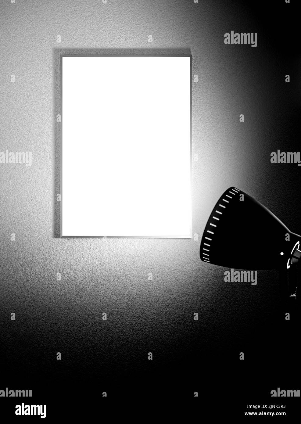 Poster verticale vuoto in una cornice sulla parete illuminata da una lampada da terra a treppiede Foto Stock