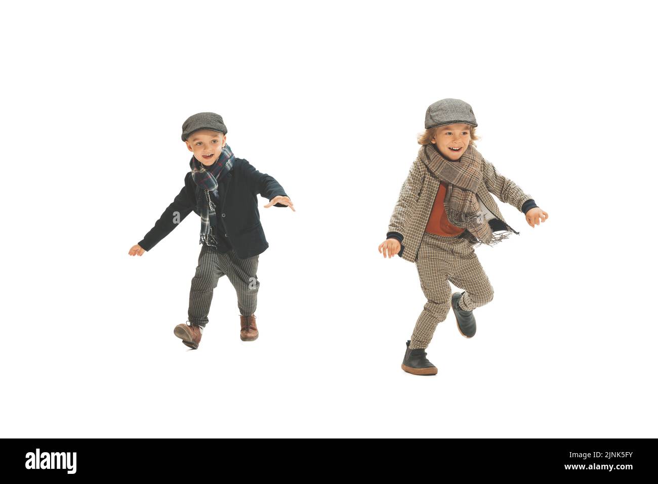Recupero. Due ragazzi dell'età prescolare, bambini alla moda che indossano abiti autunnali retrò che passeggiando isolati su sfondo bianco. Concetto di infanzia Foto Stock