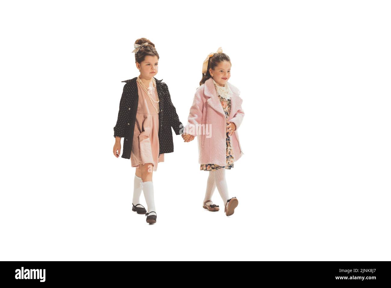 Studio girato di piccole ragazze felice in stile retrò vestito, moda di 70s, 80s anni isolato su sfondo bianco. Concetto di arte, amicizia, speranza Foto Stock